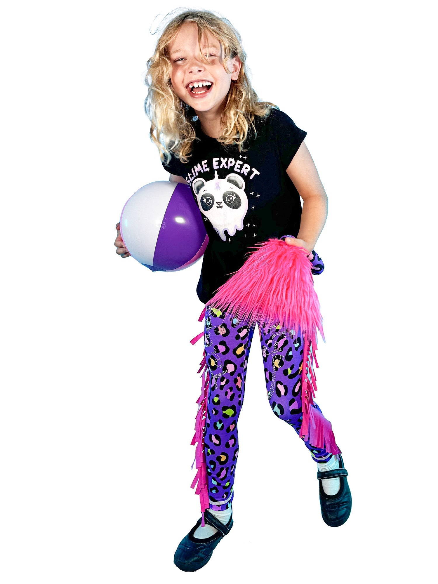 Happy girl wearing purple leopard print leggings with frills and pink tail holding beach ball