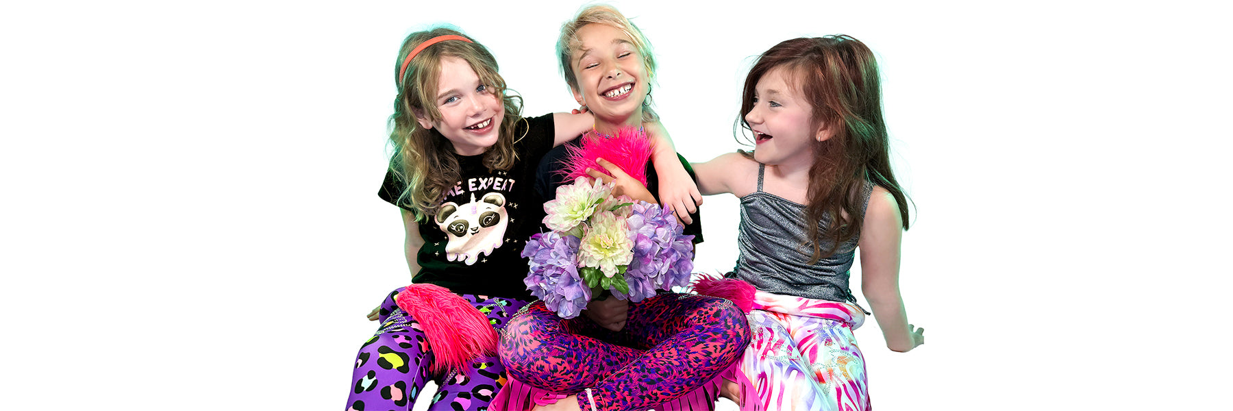 Three happy girls sitting and hugging wearing animal print leggings with tails by Tailys.